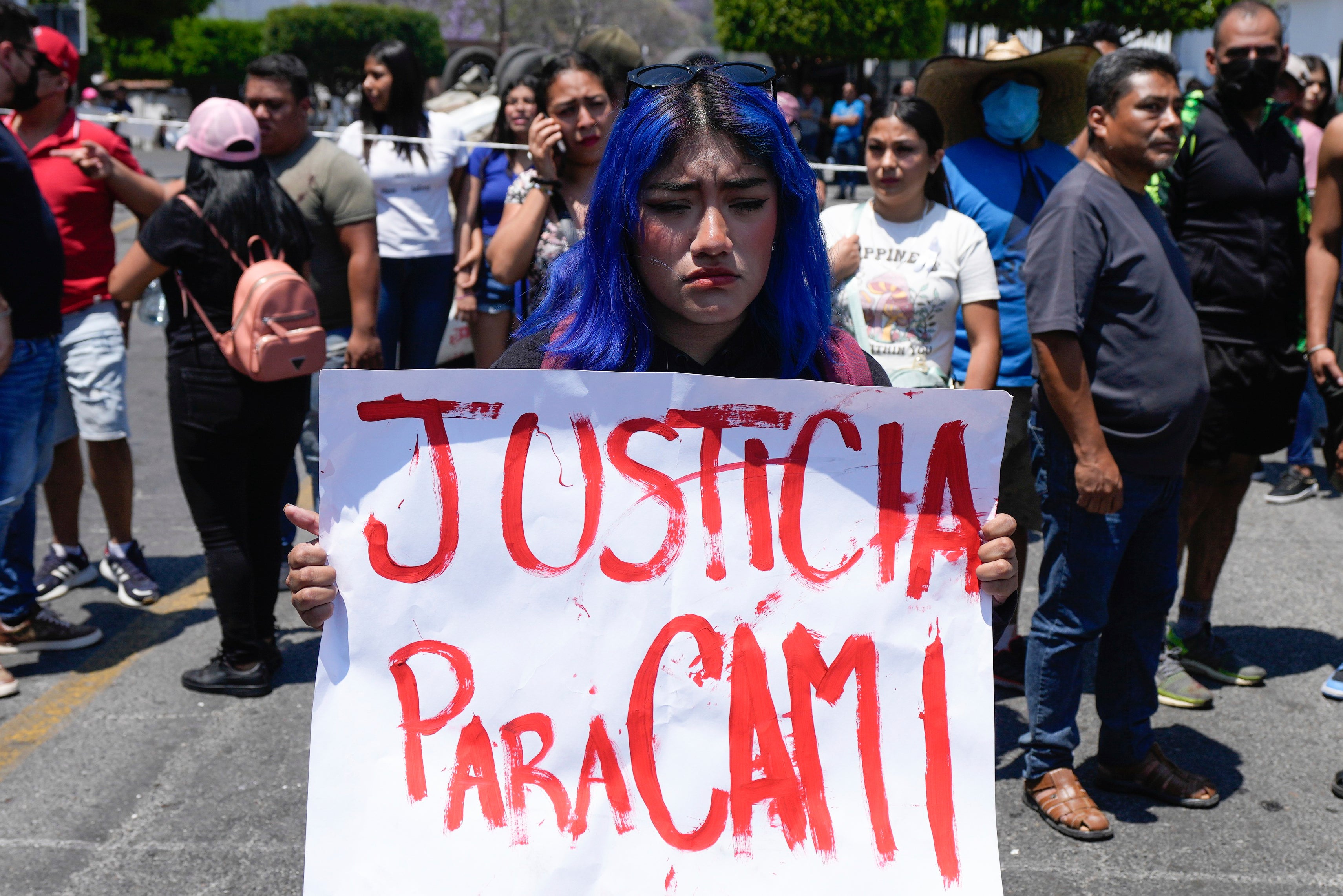 A woman holds a sign with a message that reads in Spanish: ‘Justice for Cami’