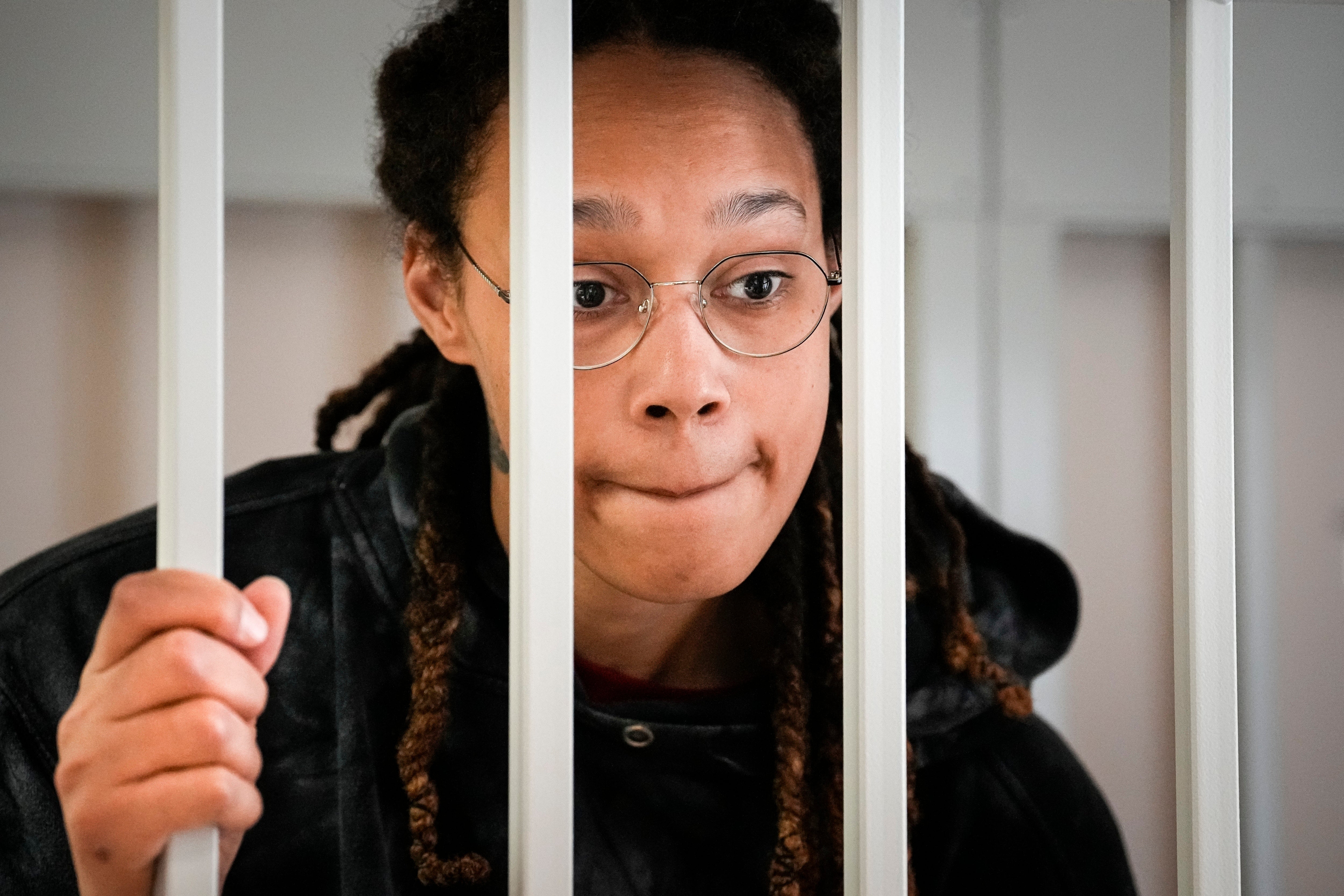 WNBA star and two-time Olympic gold medalist Brittney Griner speaks to her lawyers from inside a cage in a courtroom