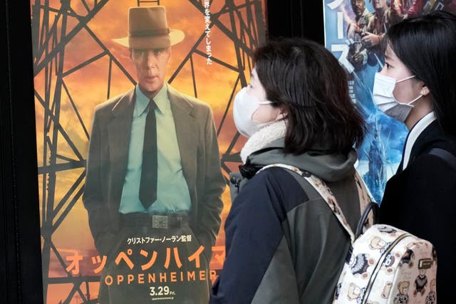 <p>People walk by a poster to promote the multiple Oscar-winning movie in Tokyo on 29 March</p>