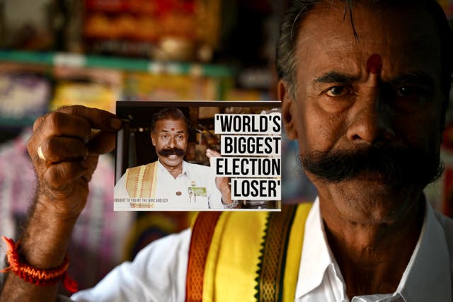 <p>Independent candidate K Padmarajan, a tyre repair shop owner shows a photograph featuring himself stating ‘World’s Biggest Election Loser’ at his office in Mettur, near Salem district in India’s Tamil Nadu state</p>