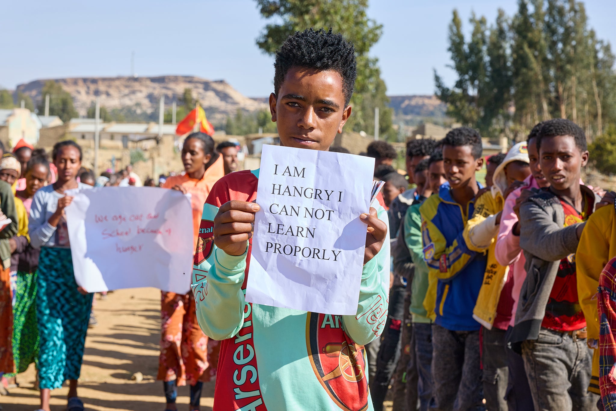 Children holding up strong messages as representatives from Mary’s Meals arrive at Gendet Primary School