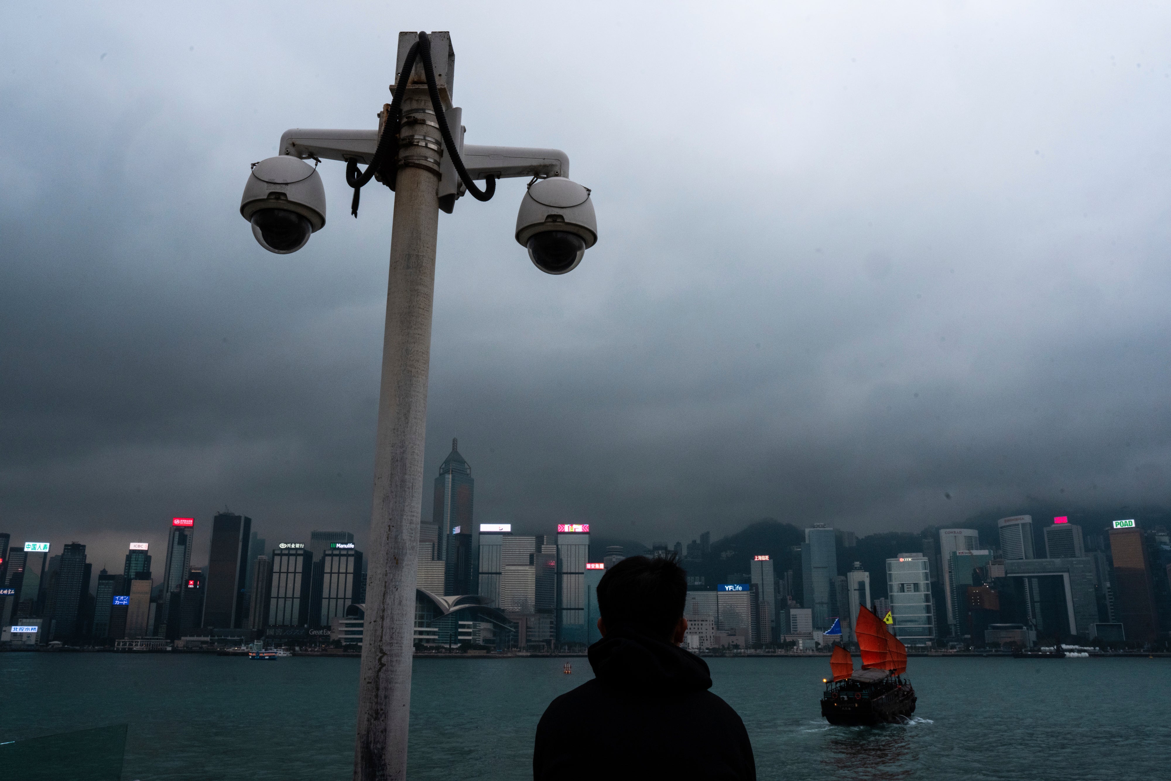File: Surveillance cameras are seen as a visitor looks at Victoria Harbour in Hong Kong on 11 March 2024