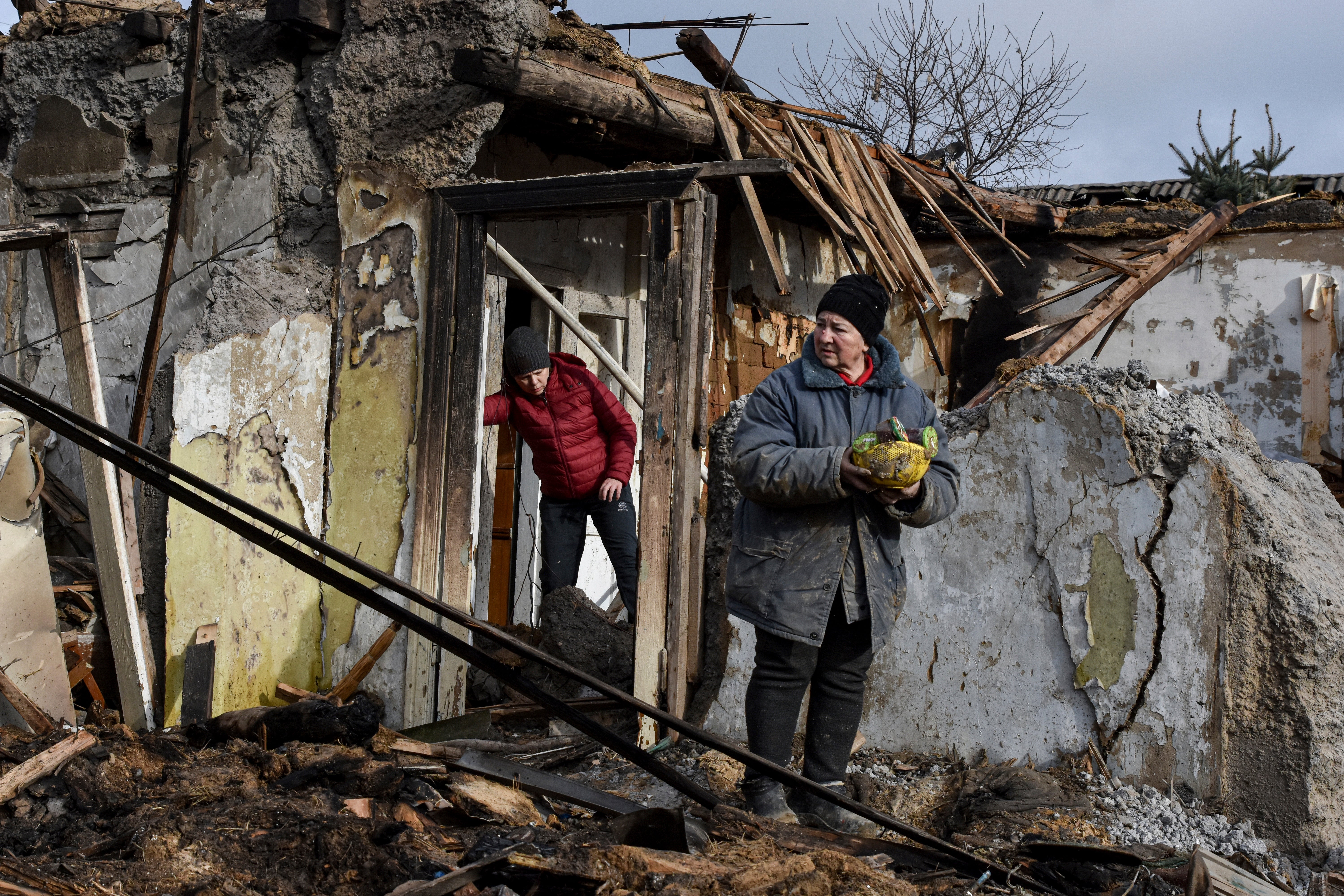 Inna, 71, holds food items found as she stands outside her house which was destroyed by a Russian drone attack