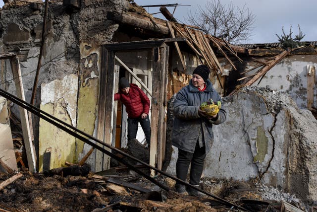 <p>Inna, 71, holds food items found as she stands outside her house which was destroyed by a Russian drone attack </p>
