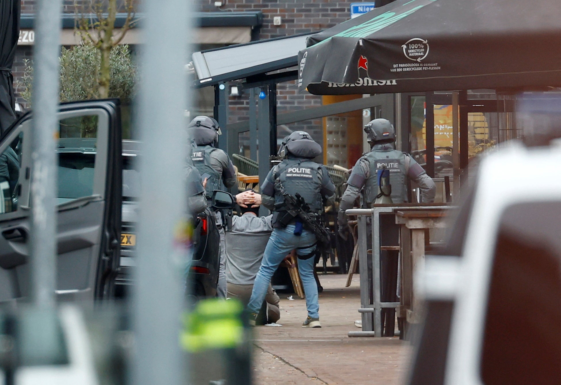 Dutch police officers detain a person outside the Cafe Petticoat, where several people were being held hostage in Ede