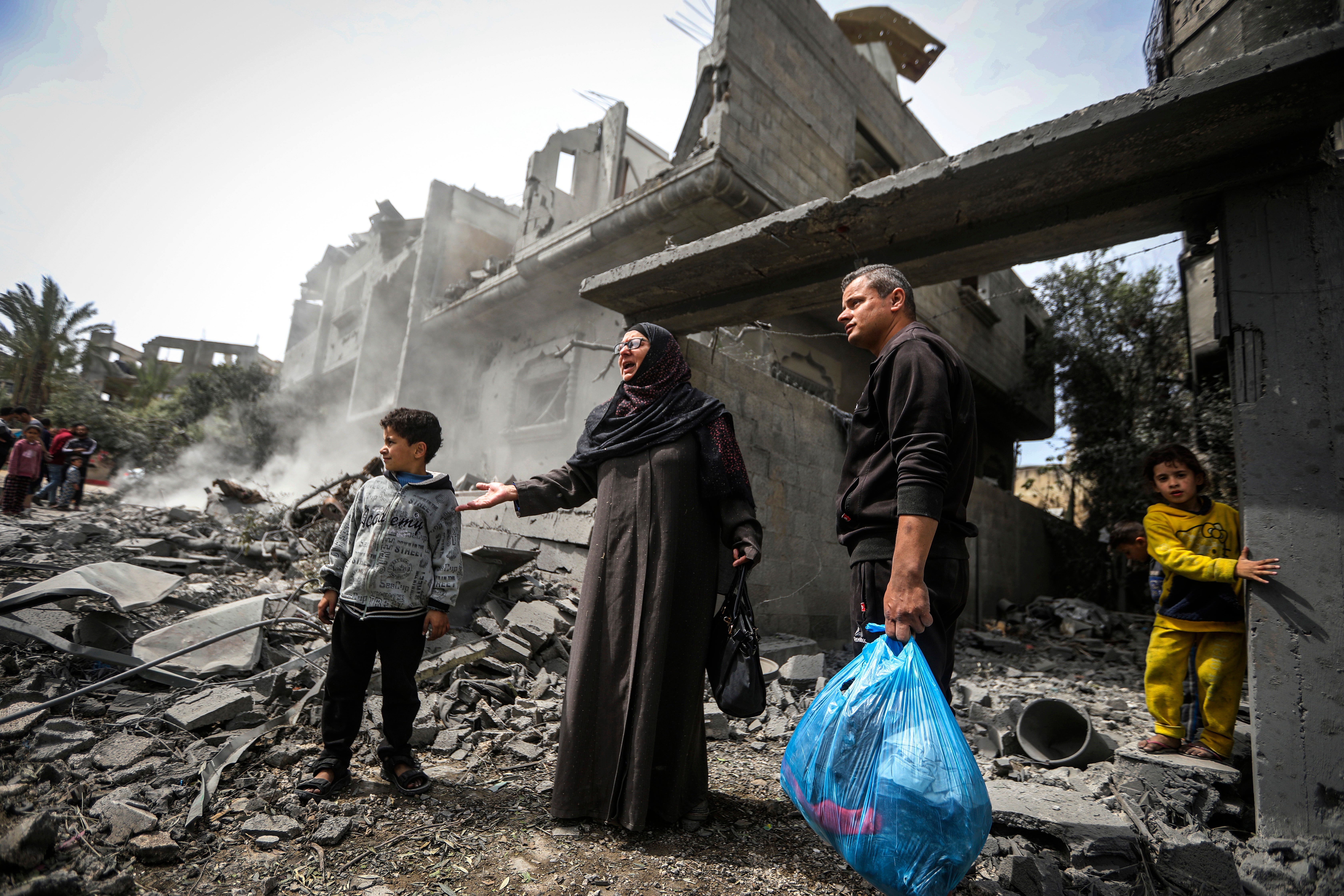 Palestinians collect their belongings from the rubble of a residential building after an Israeli airstrike in the Maghazi refugee camp in the Gaza Strip