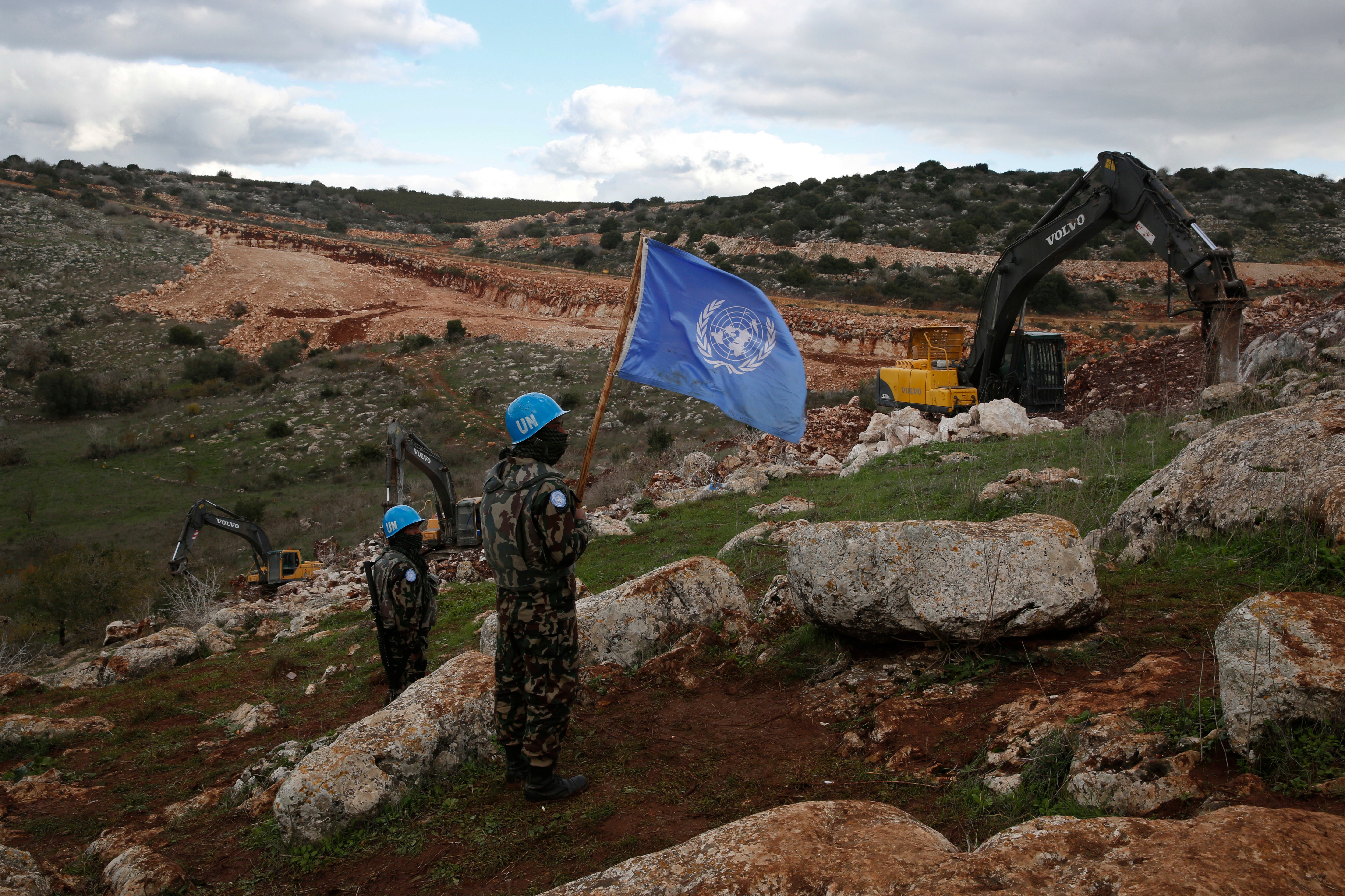 UN peacekeepers hold their flag as they observe Israeli excavators attempting to destroy tunnels built by Hezbollah near the border in 2019