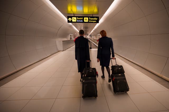 <p>Flight attendants arriving at the Henri Coanda International Airport pass under a Schengen Information sign</p>