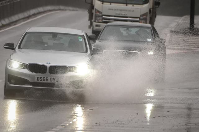 <p>Cars drive through the rain on the A3 (Aaron Chown/PA)</p>