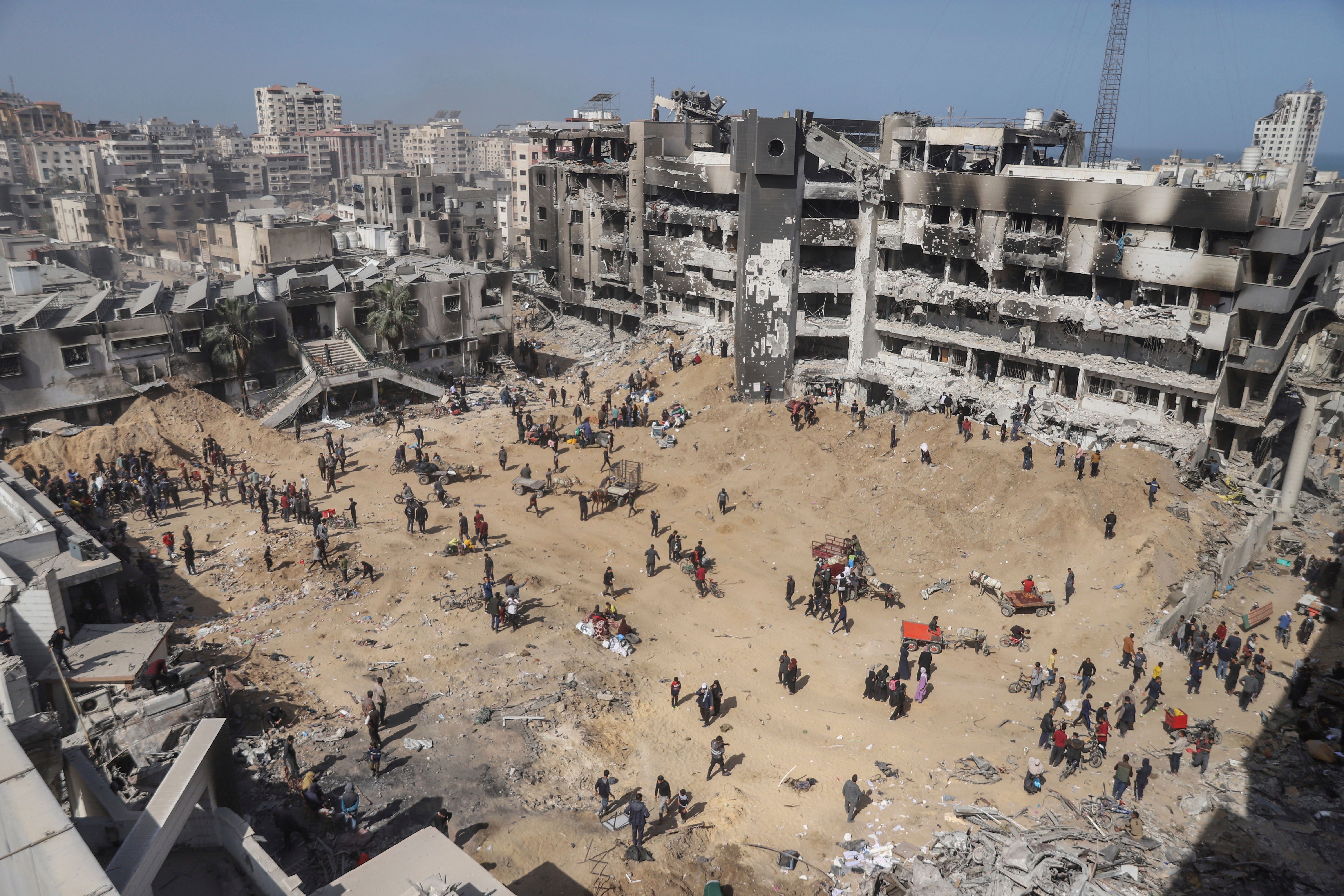 Palestinians walk through the destruction left by the Israeli air and ground offensive on the Gaza Strip near Shifa Hospital in Gaza City