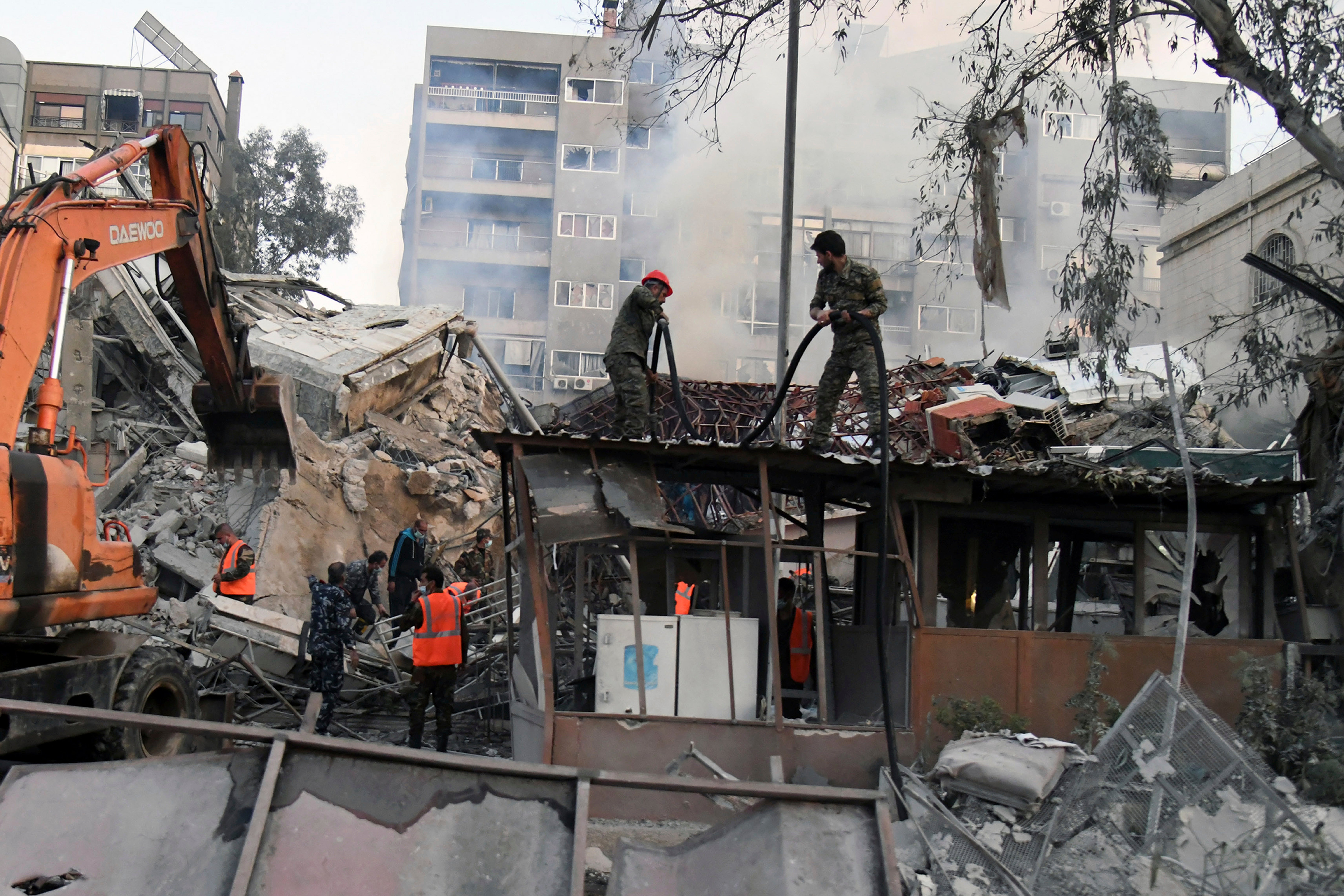 Emergency service workers clear the rubble at a destroyed building struck in Damascus