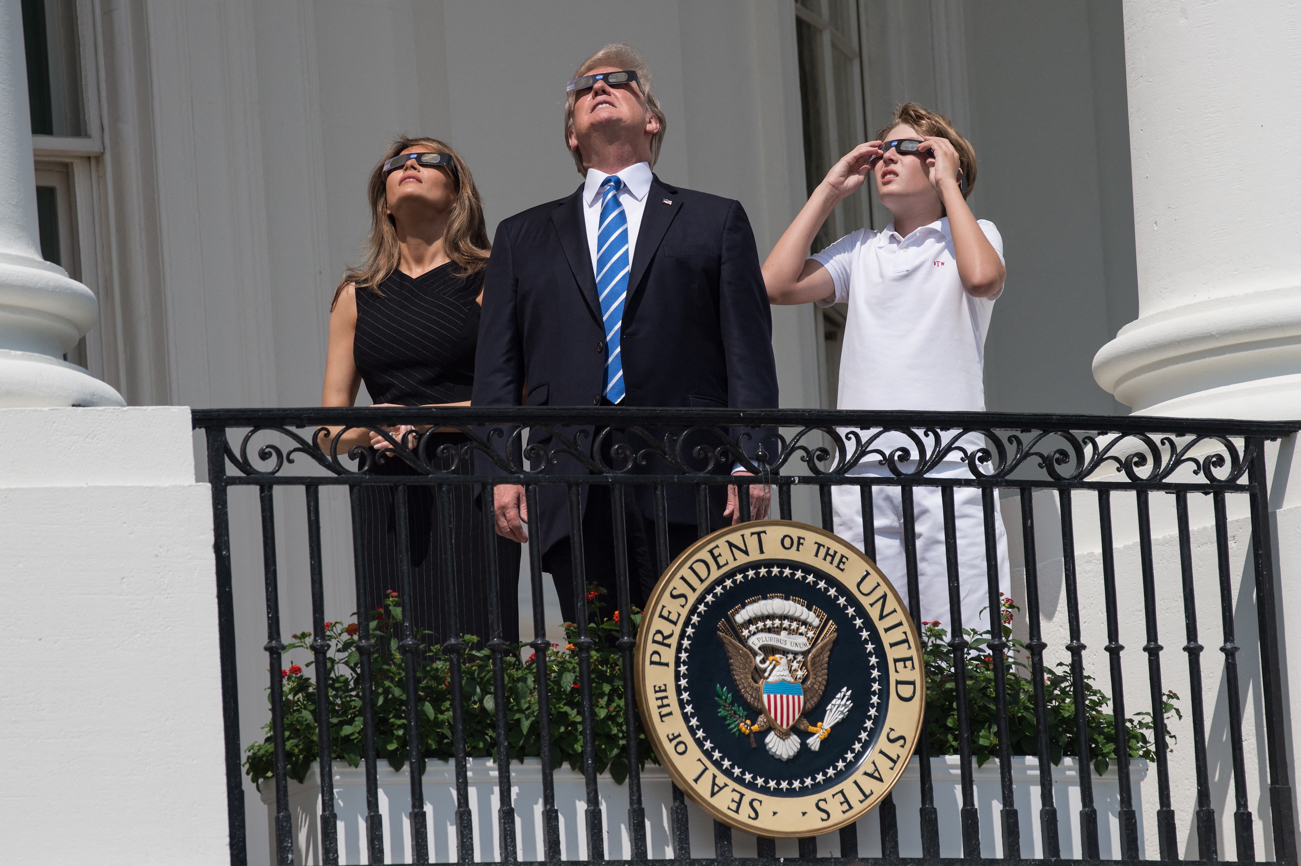 A young Barron Trump joins his parents on the White House balcony to observe a solar eclipse on 21 August 2017