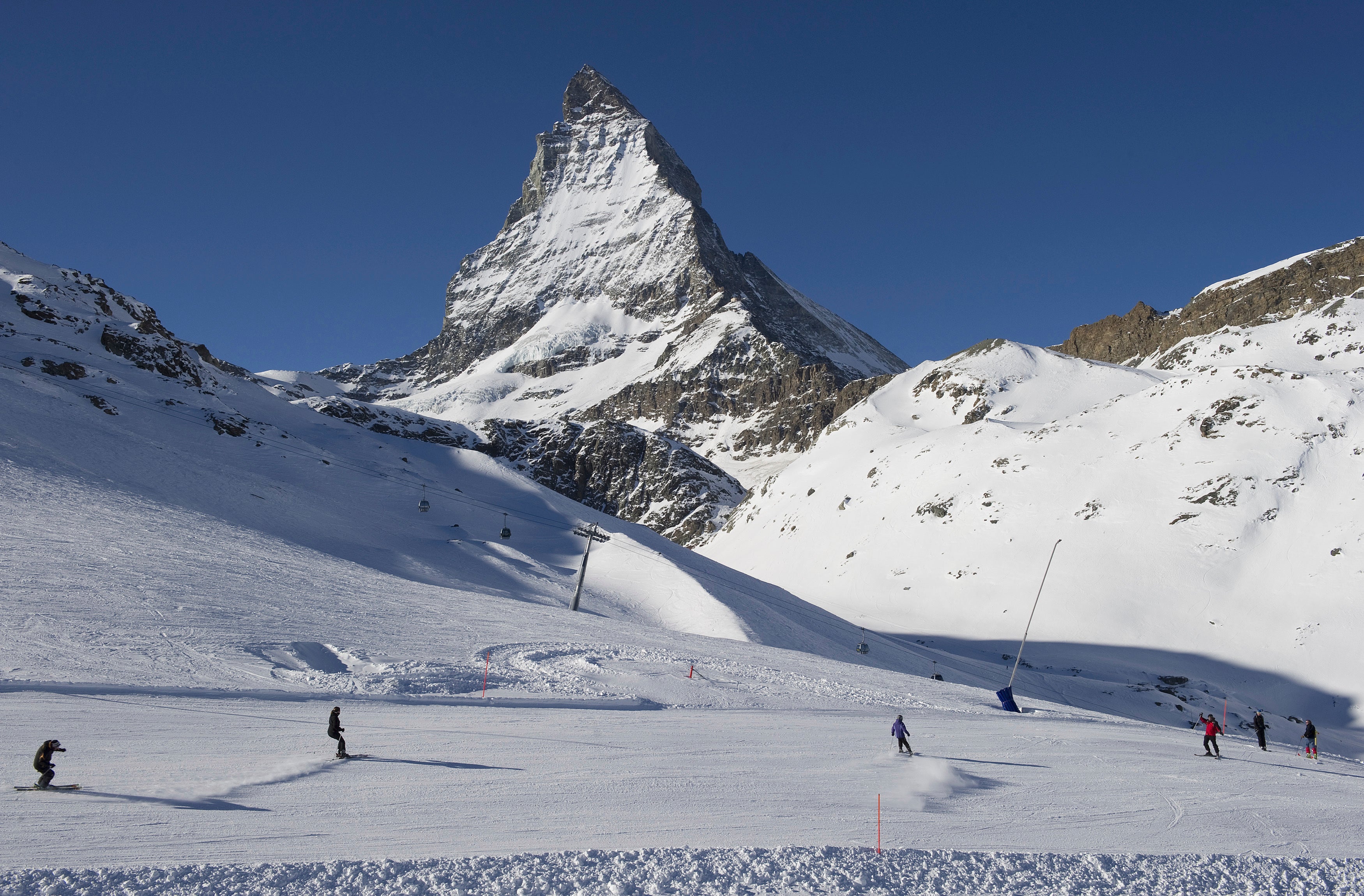 Skiers ride down the slopes at Riffelberg with Mount Matterhorn in the background