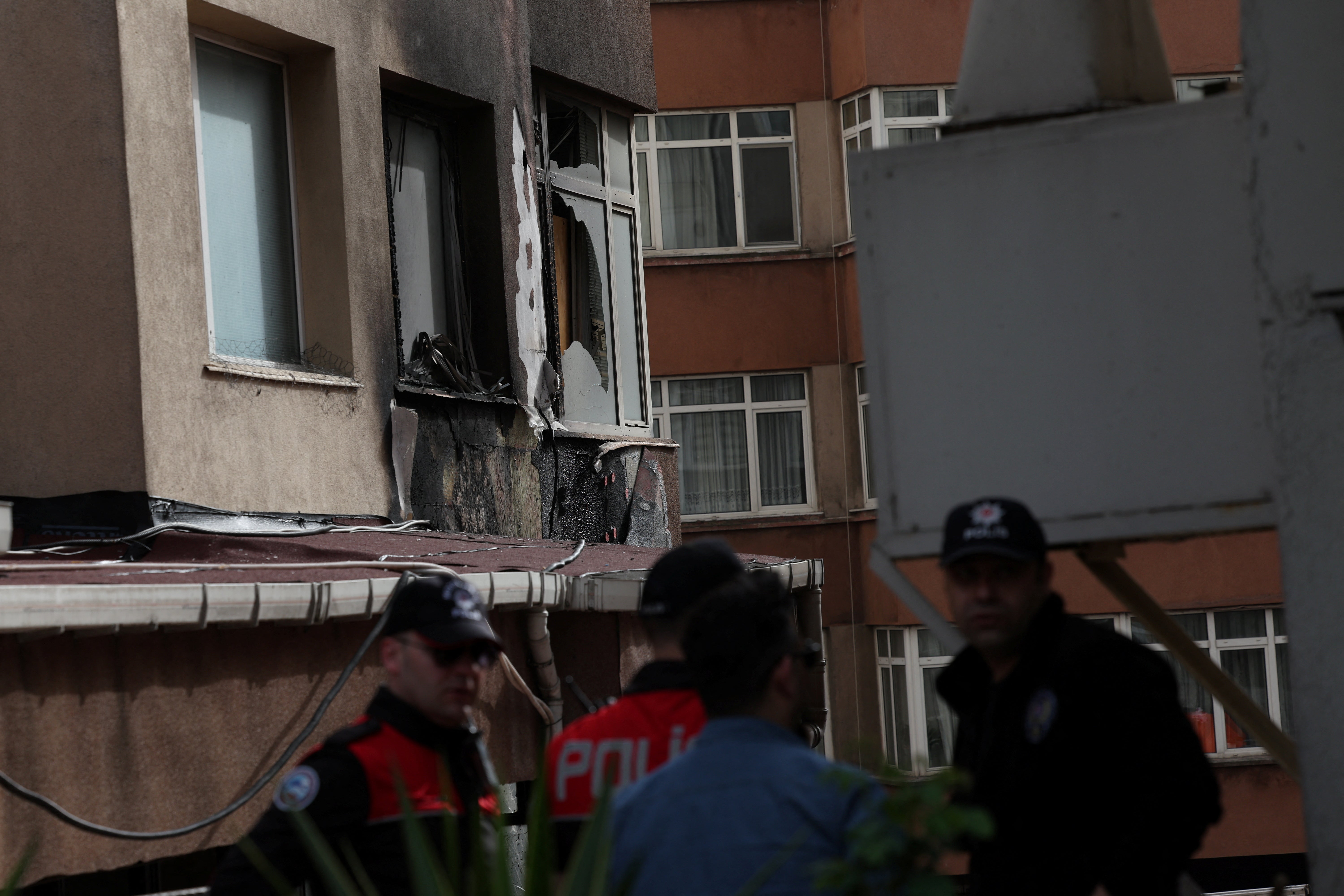 Police officers stand next to a building after a fire broke out during daytime renovation work