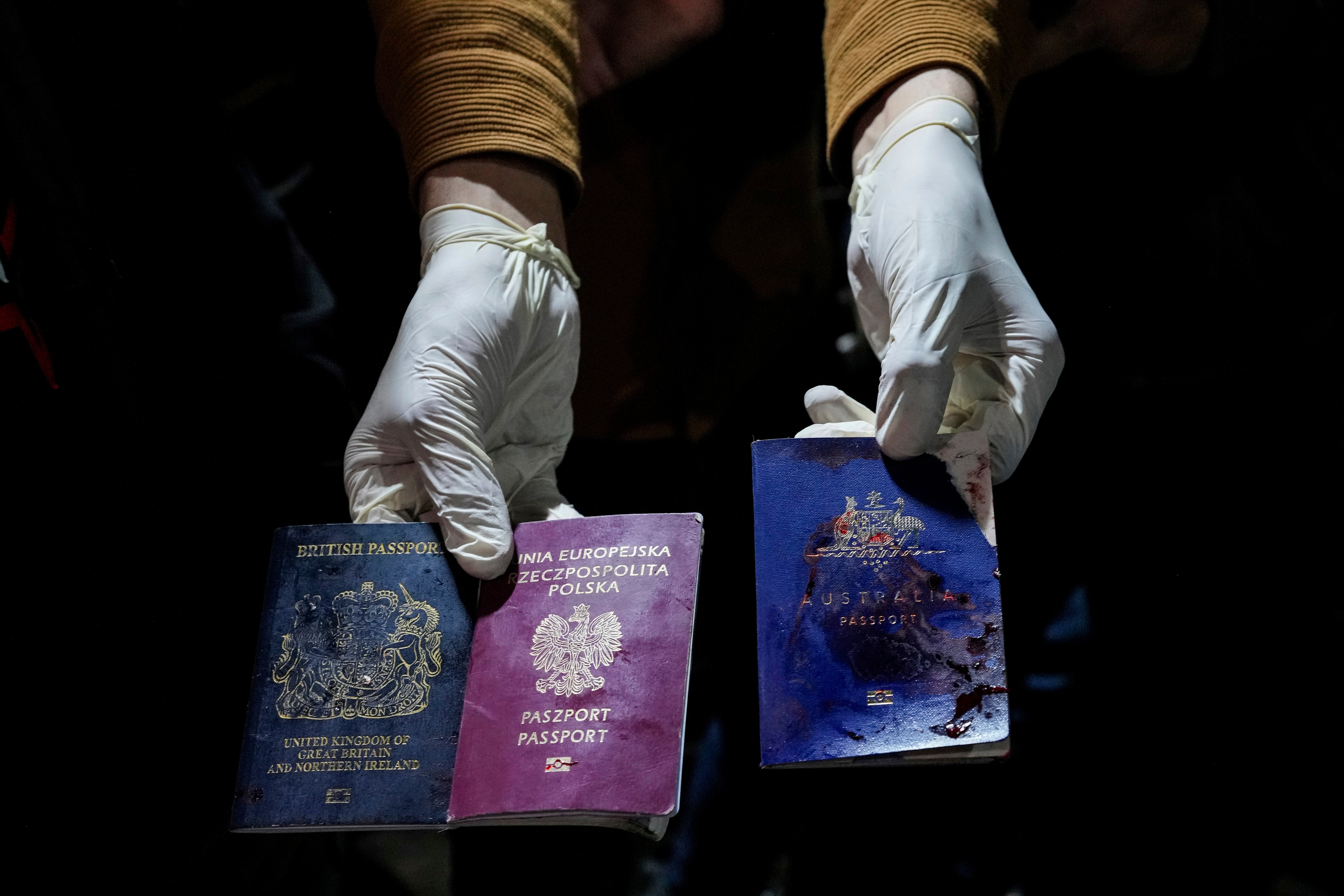 A man displays blood-stained British, Polish, and Australian passports following the Israeli airstrike
