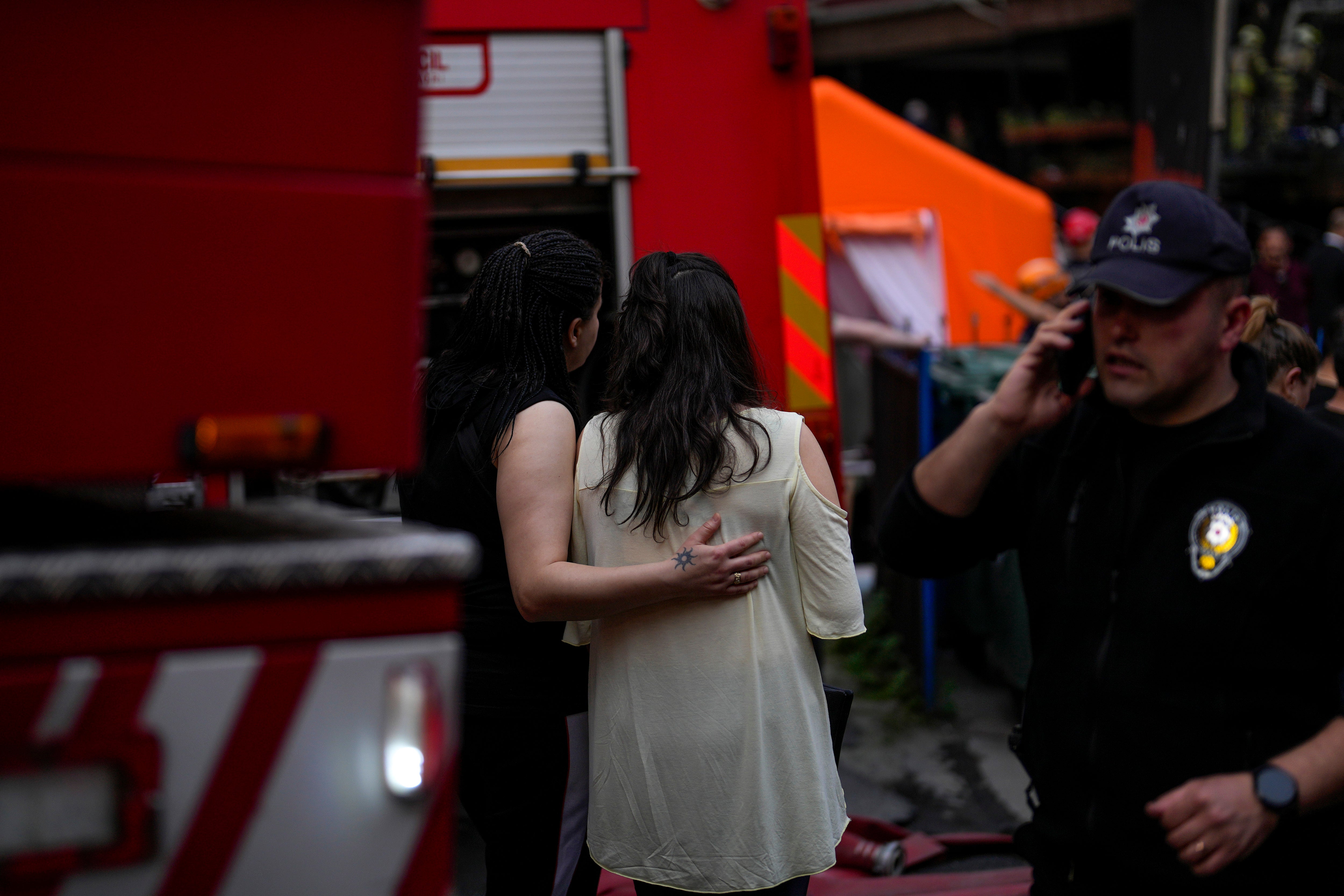 Two women gather as firefighters and emergency teams work in the aftermath of a fire in a nightclub in Istanbul