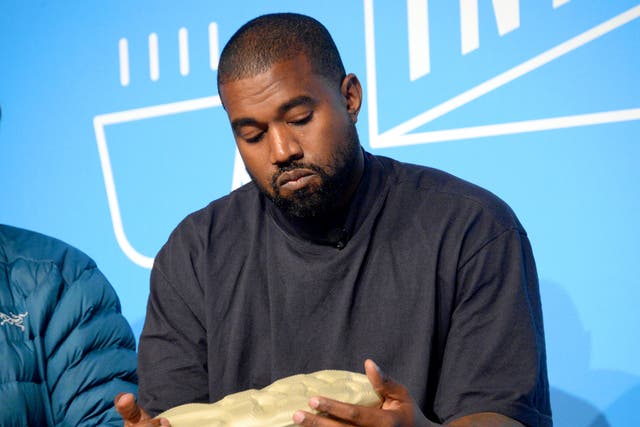 <p>Kanye West holding a Yeezy shoe in 2019</p>