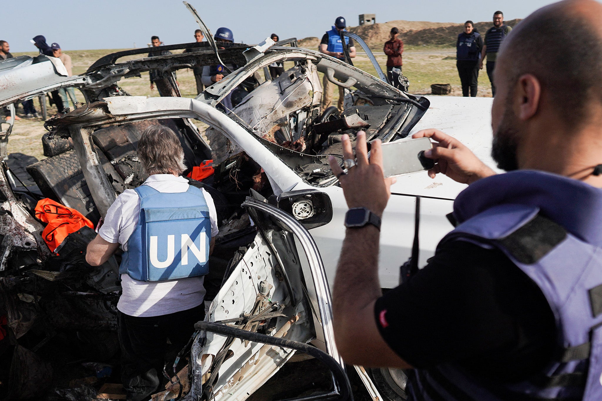 United Nations staff members inspect the wreckage of a car used by WCK