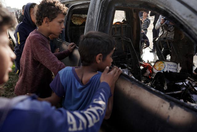 <p>People gather around the ruins of a car used by US-based aid group World Central Kitchen that was hit by an Israeli strike</p>