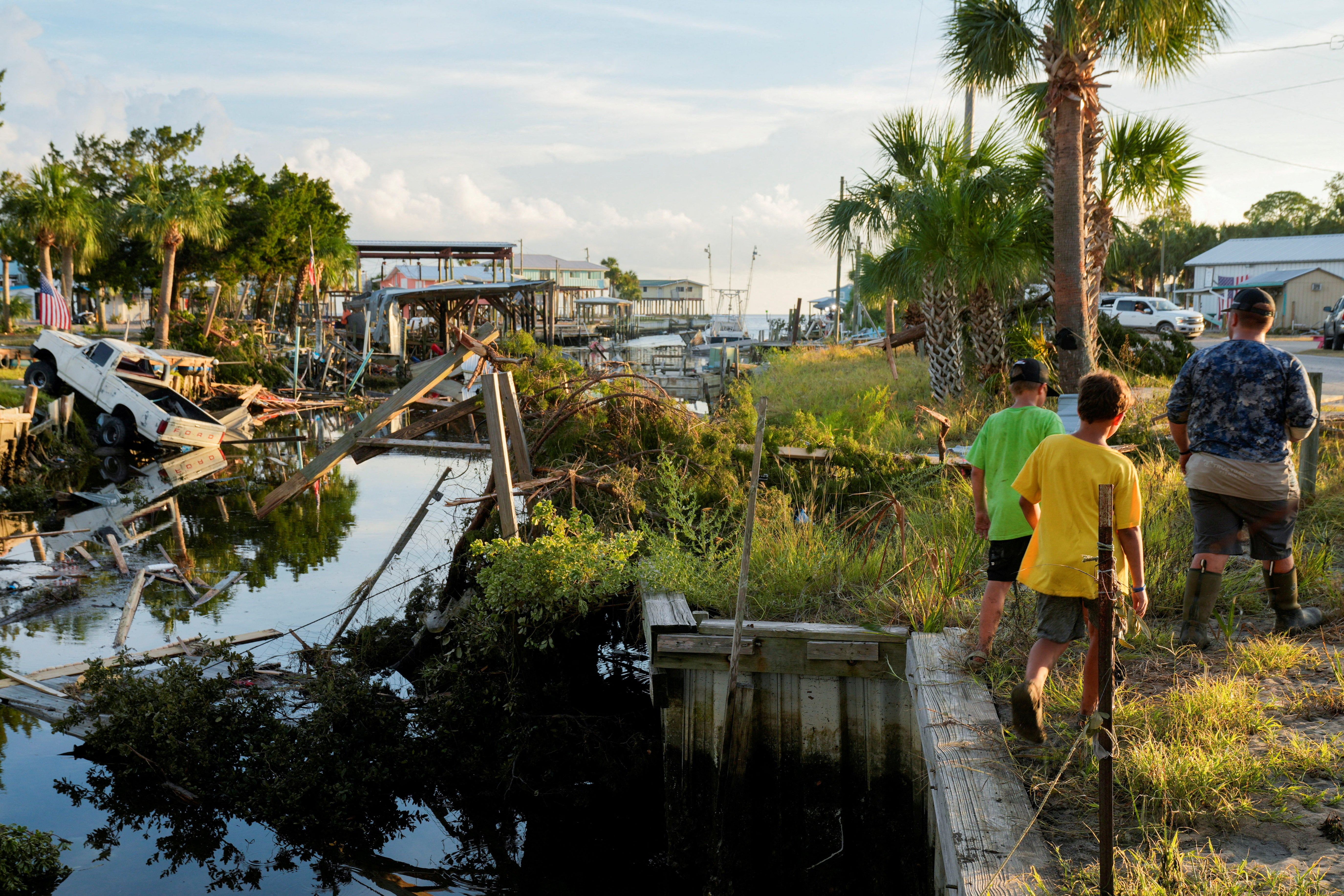 The Rollison brothers Landon, 17, Lawton, 12, and Lane, 11, walk past a canal littered with debris after the arrival of Hurricane Idalia in their hometown of Horseshoe Beach, Florida on August 31, 2023