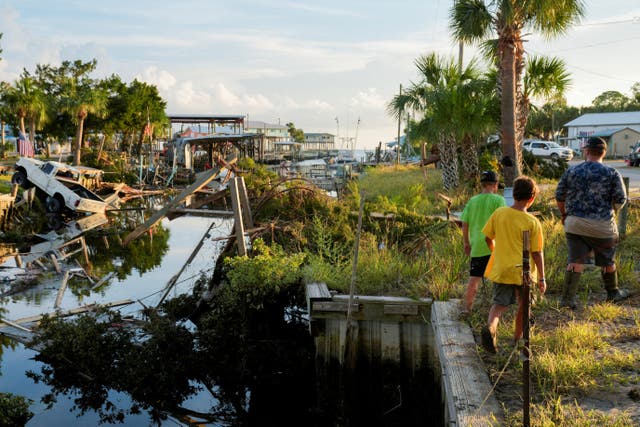 <p>The Rollison brothers Landon, 17, Lawton, 12, and Lane, 11, walk past a canal littered with debris after the arrival of Hurricane Idalia in their hometown of Horseshoe Beach, Florida on August 31, 2023</p>