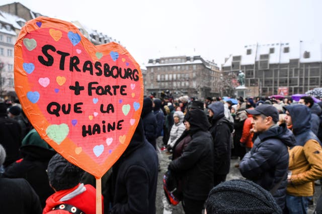 <p>File: A woman holds a sign reading “Strasbourg stronger than hate”  as she attends a gathering around a makeshift memorial at Place Kleber in  Strasbourg </p>