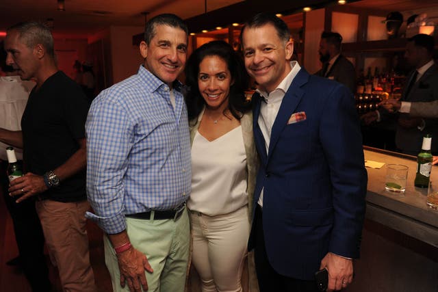 <p>Cathy Tusiani in the centre with her husband, Michael Tusiani on the right at a  Miami Beach party in 2017 </p>