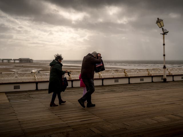 <p>People brave the wind and rain on Blackpool’s North Pier during Storm Kathleen </p>