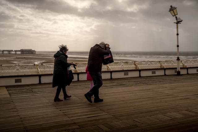 <p>People brave the wind and rain on Blackpool’s North Pier during Storm Kathleen </p>