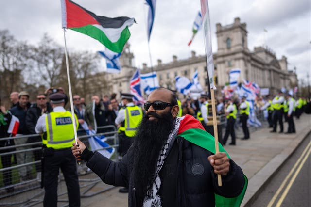 <p>A man waving Palestinian flags walks past pro-Israel supporters during a march to mark Al Quds Day </p>