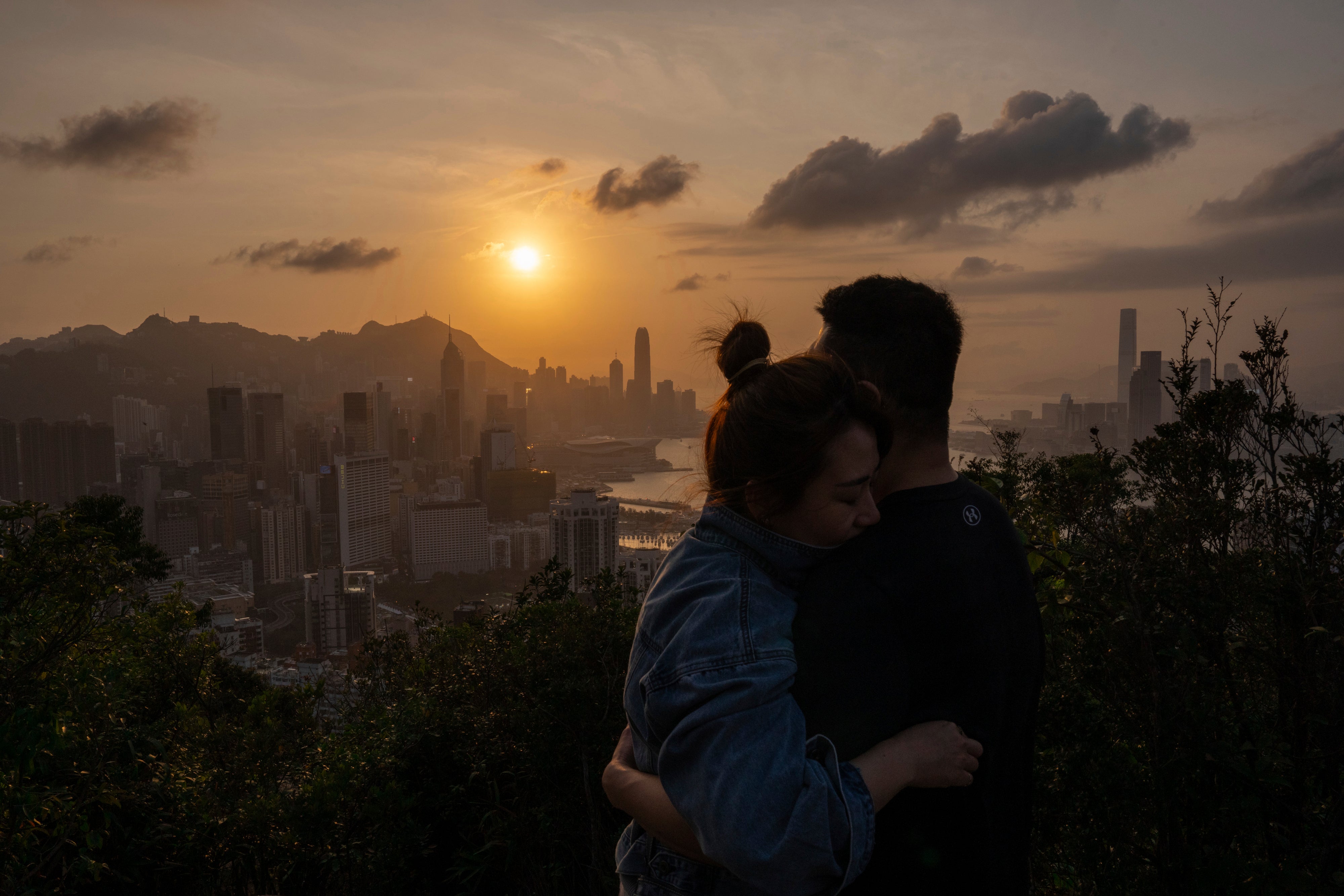 Visitors look at sunset from a hill in Hong Kong, Friday, March 22, 2024.