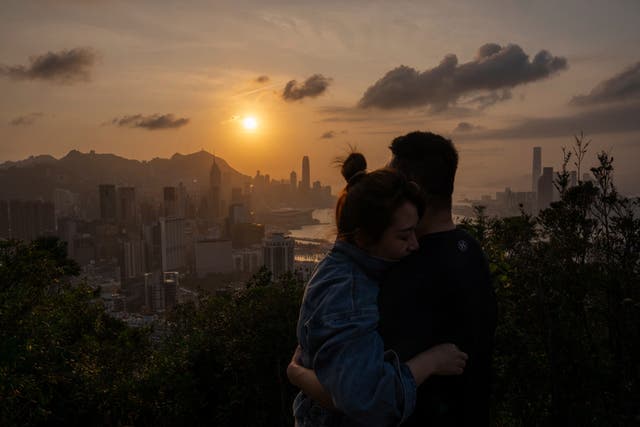 <p>Visitors look at sunset from a hill in Hong Kong, Friday, March 22, 2024. </p>