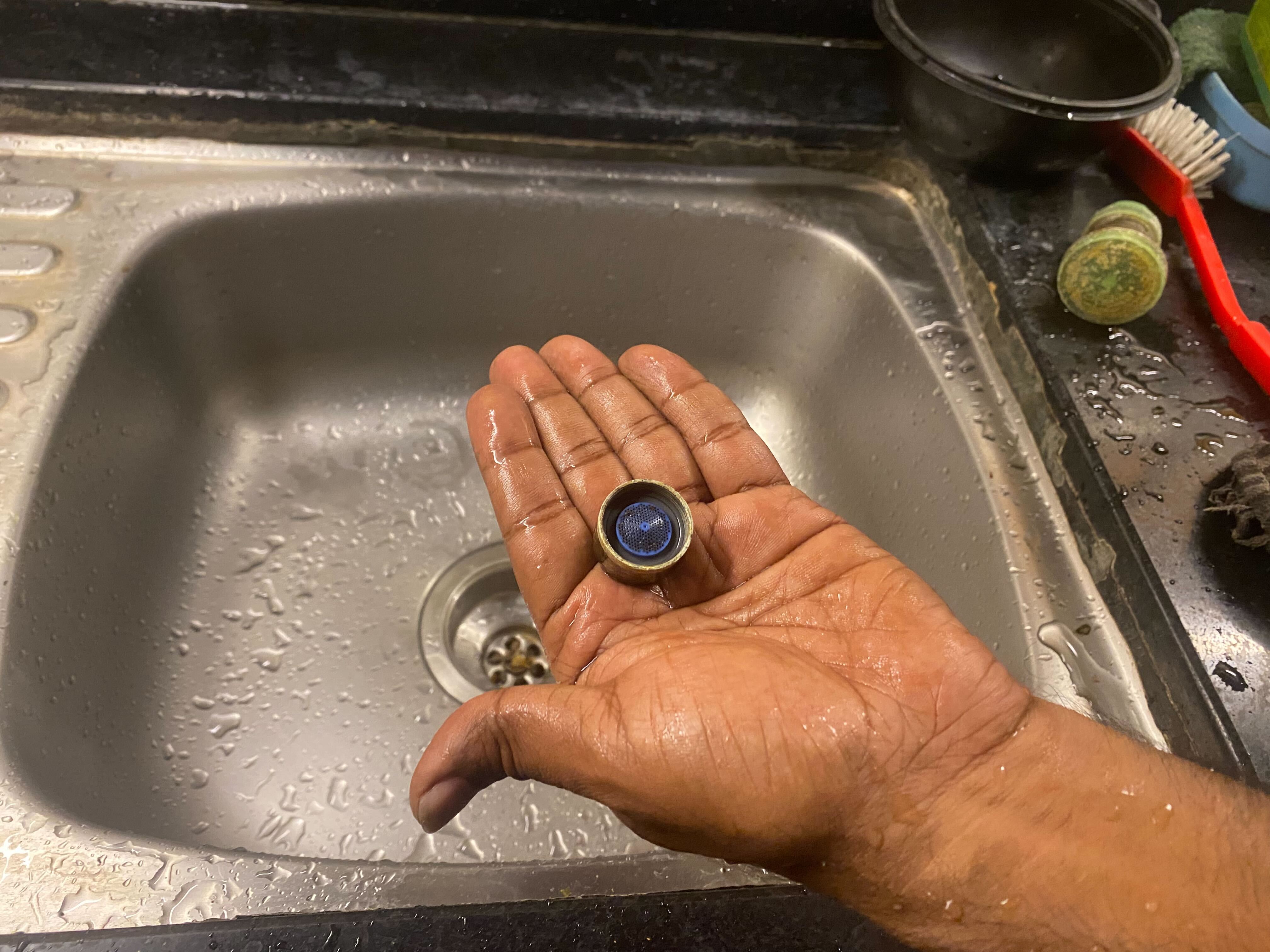 A resident shows a device for reducing the flow of water from a tap. Such devices have been installed in many apartments to regulate water supply amid the shortage