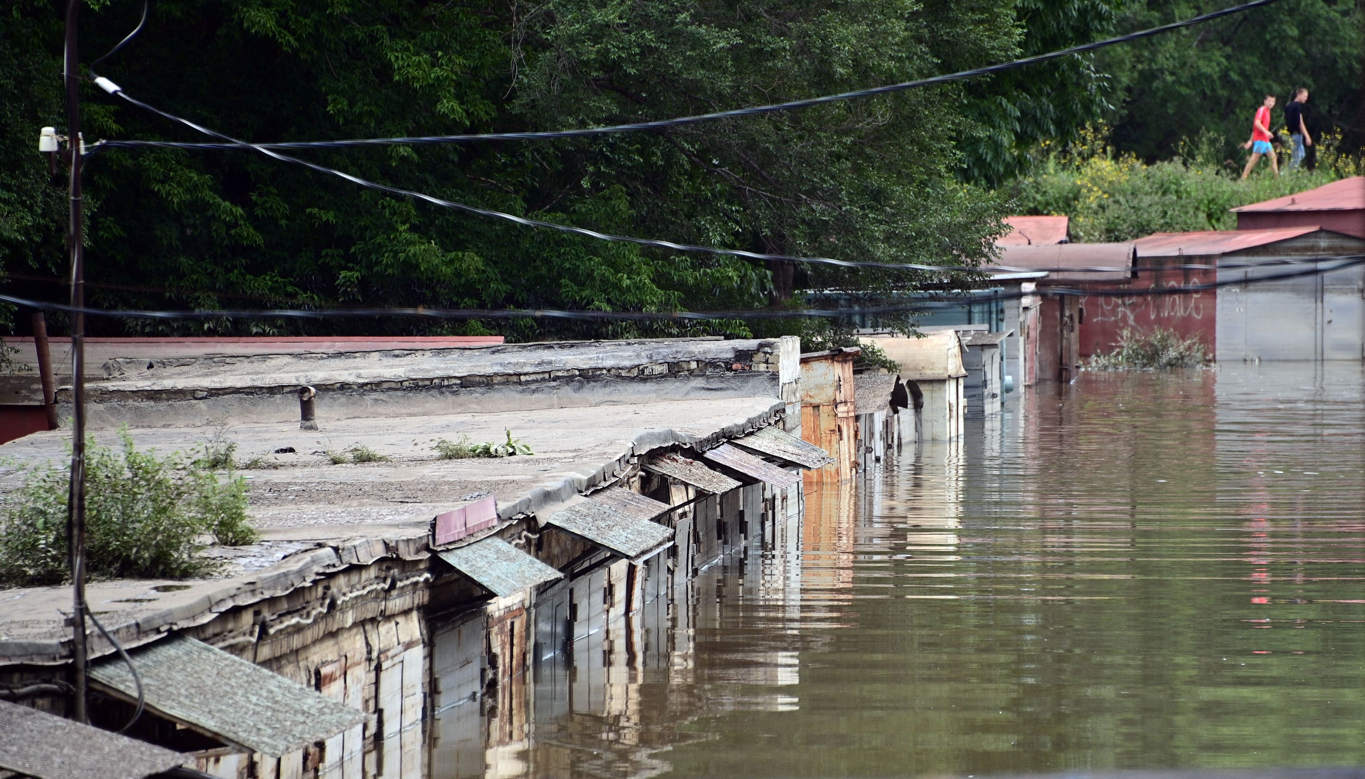 <p>Pedestrians walk past a flooded area of the Russian far-eastern city of Ussuriysk on August 14, 2023</p>