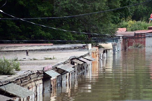 <p>Pedestrians walk past a flooded area of the Russian far-eastern city of Ussuriysk on August 14, 2023</p>