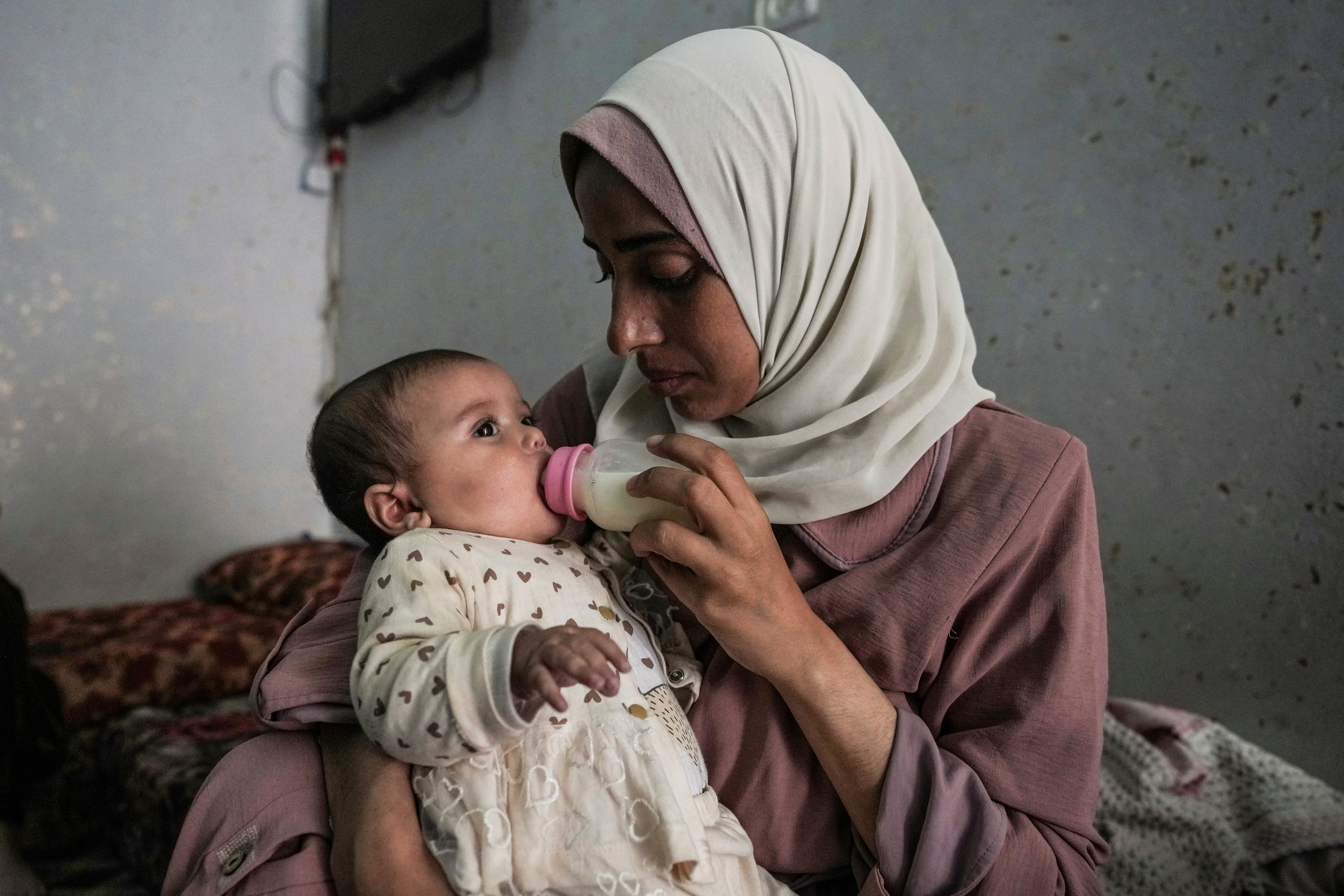 A mother, displaced by the Israeli attacks, feeds her baby in Nuseirat, a refugee camp in Gaza
