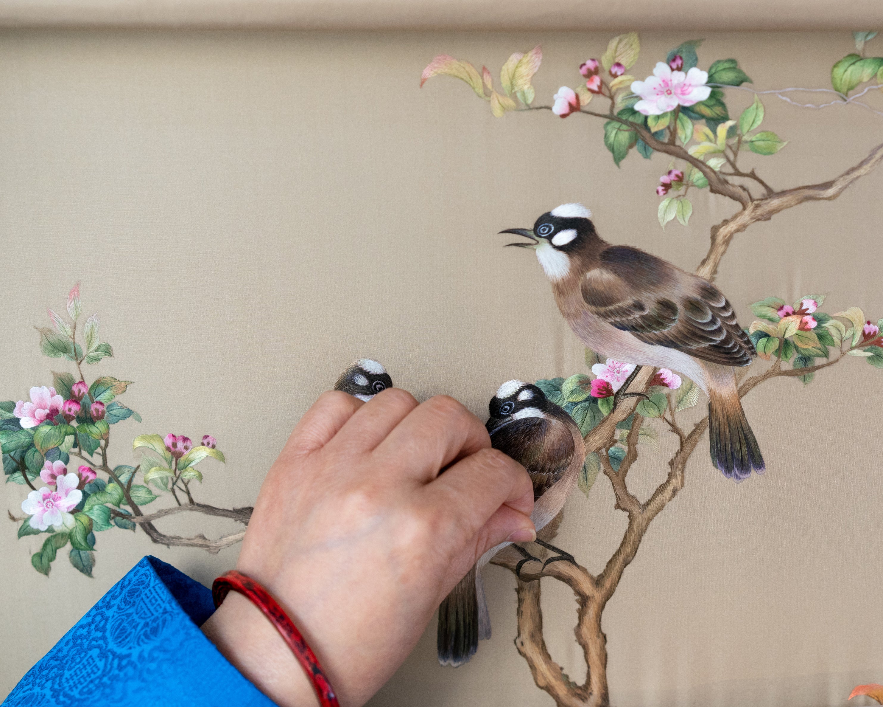 A flock of birds come alive in the skilled hands of Fu Xianghong, a master of Su embroidery known for her flower-and-bird works