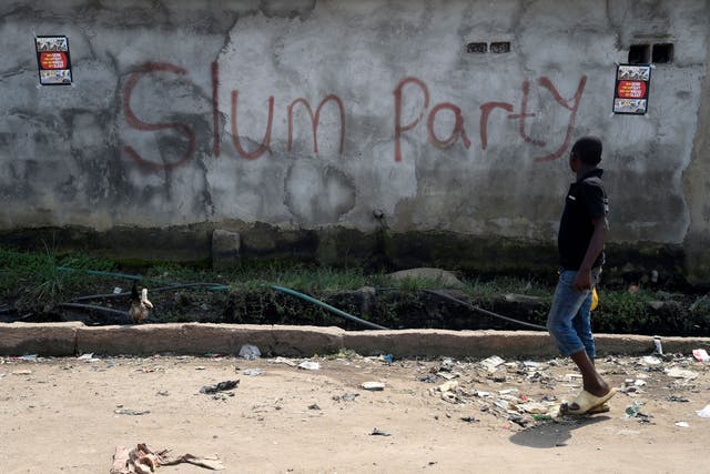 <p>A man walks by a slum in Nigeria's Lagos </p>