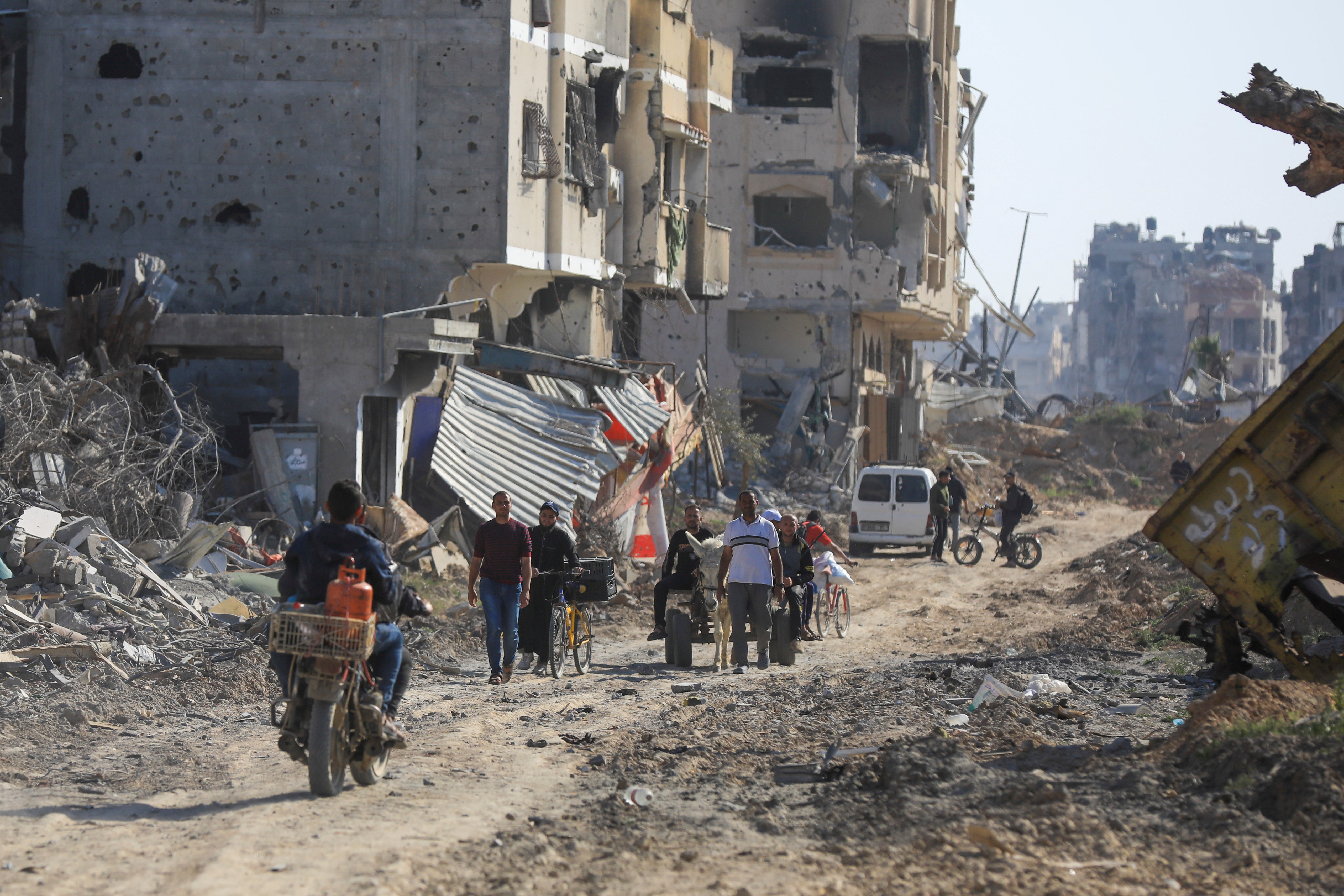 Palestinians walk through the destruction left by the Israeli air and ground offensive after they withdrew