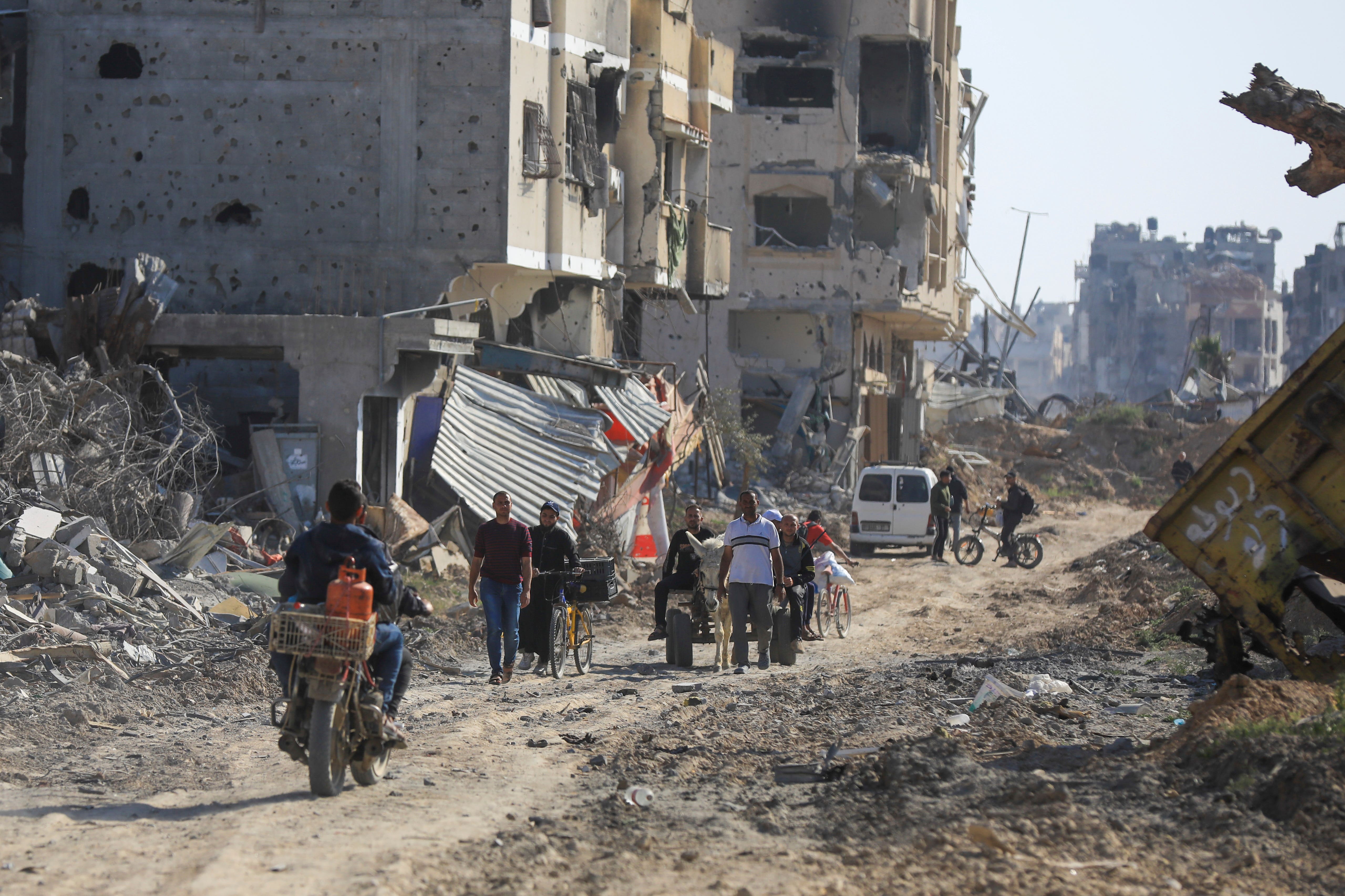 Palestinians walk through the destruction yesterday left by the Israeli air and ground offensive in Khan Younis