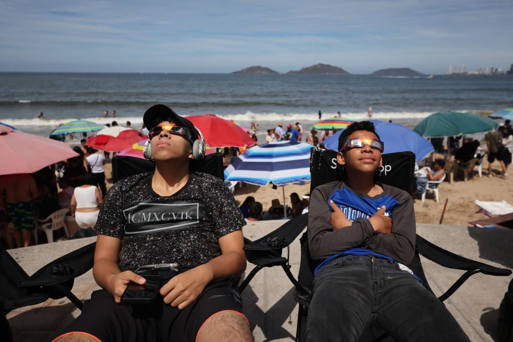 Kids use glasses to enjoy the eclipse from the beach on 8 April, 2024 in Mazatlan, Mexico
