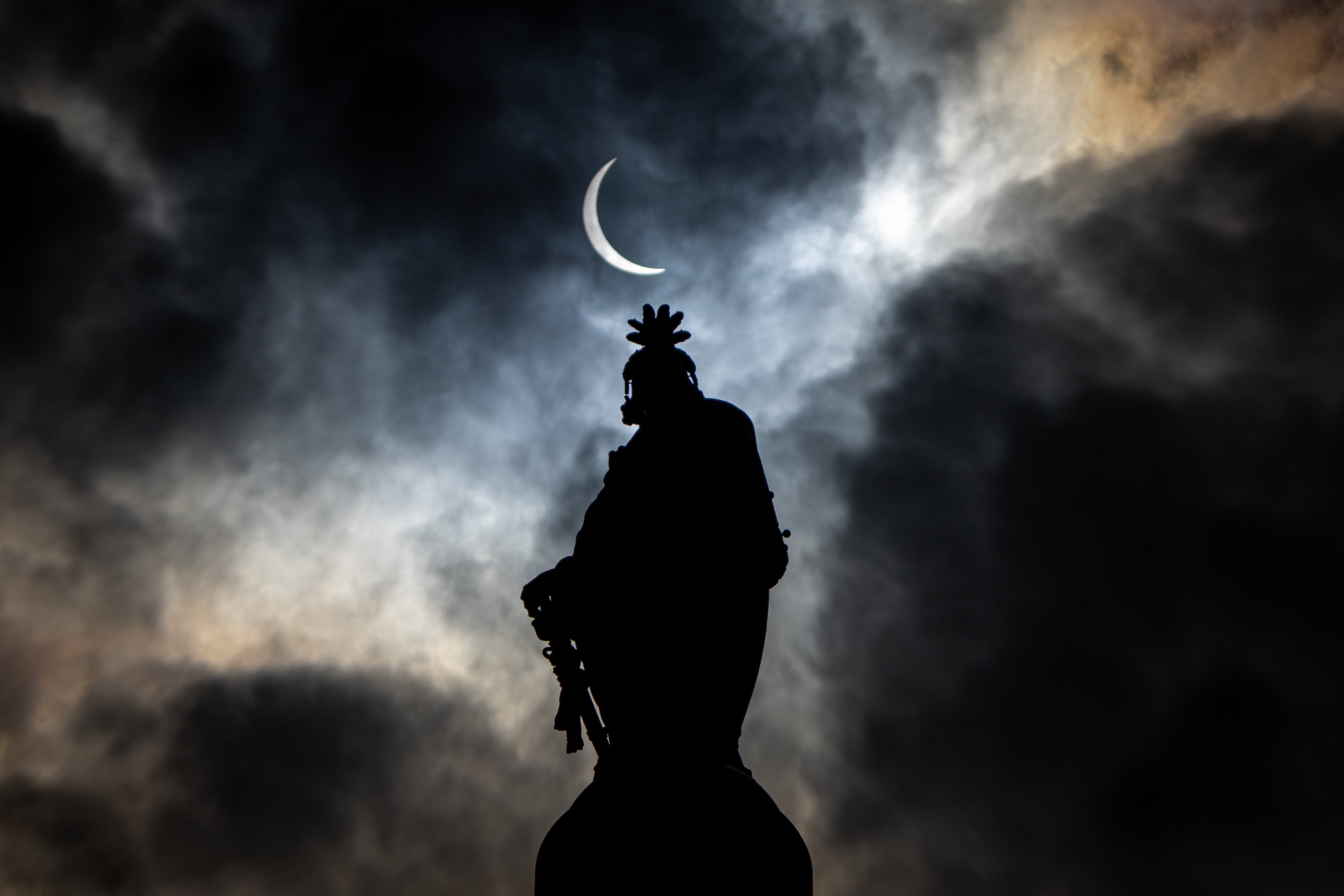 The partial solar eclipse is seen above the Statue of Freedom atop the dome of the U.S. Capitol Building on Capitol Hill