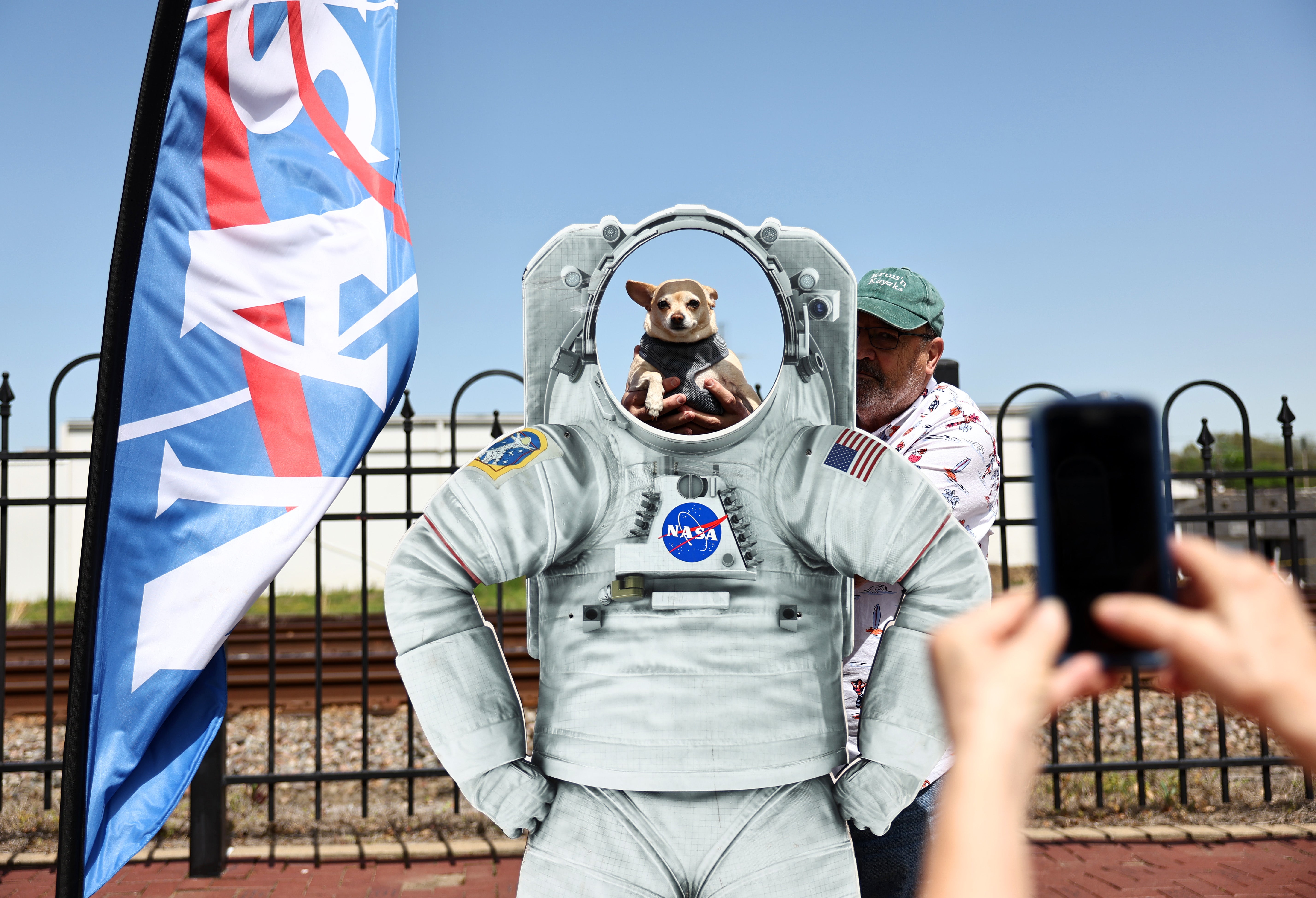 A person photographs a dog at a NASA display during the town's celebration of the April 8 solar eclipse