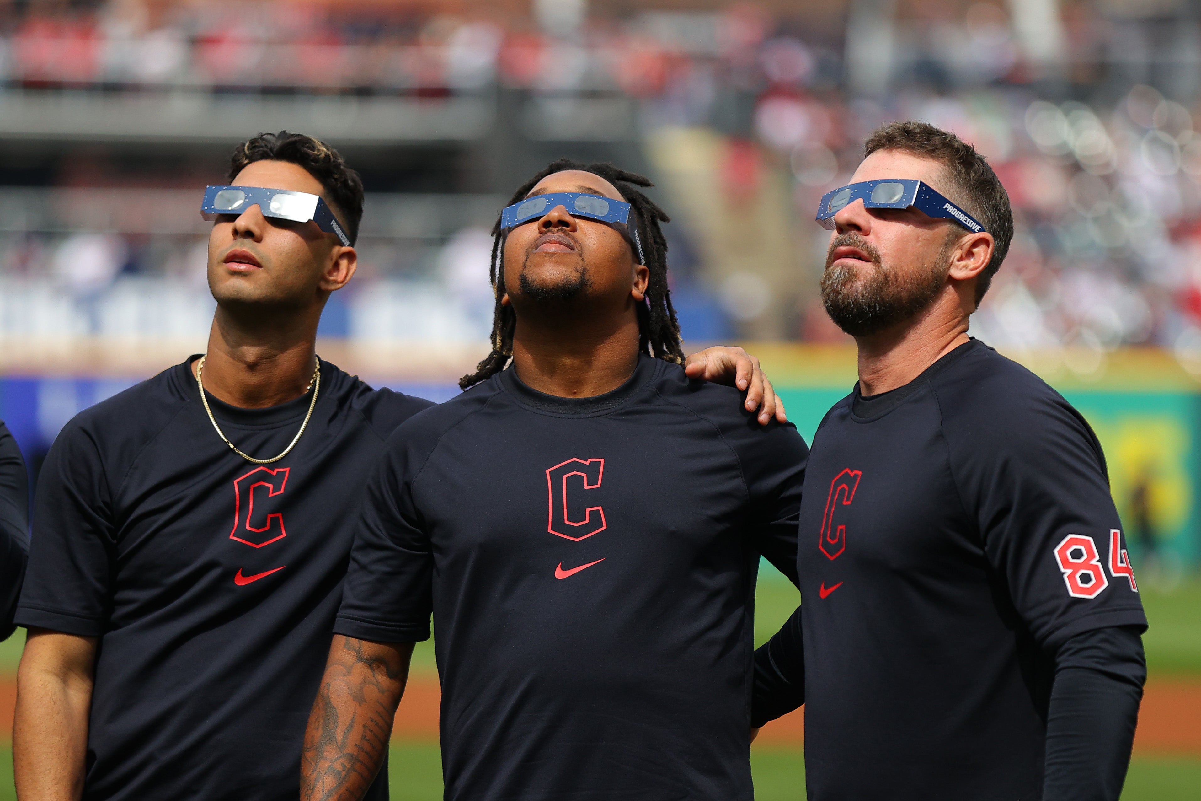 Brayan Rocchio #4, José Ramírez #11 and J.T. Maguire #84 of the Cleveland Guardians look up at the total solar eclipse before the home opener against the Chicago White Sox at Progressive Field