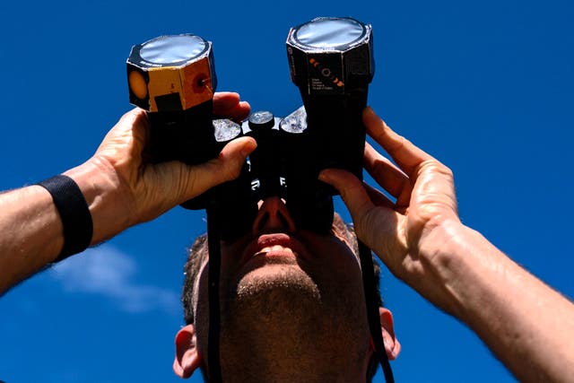 <p>Frederik De Vries looks up at the sun during the solar eclipse using binoculars outfitted with special film in Washington, DC, on 8 April, 2024</p>