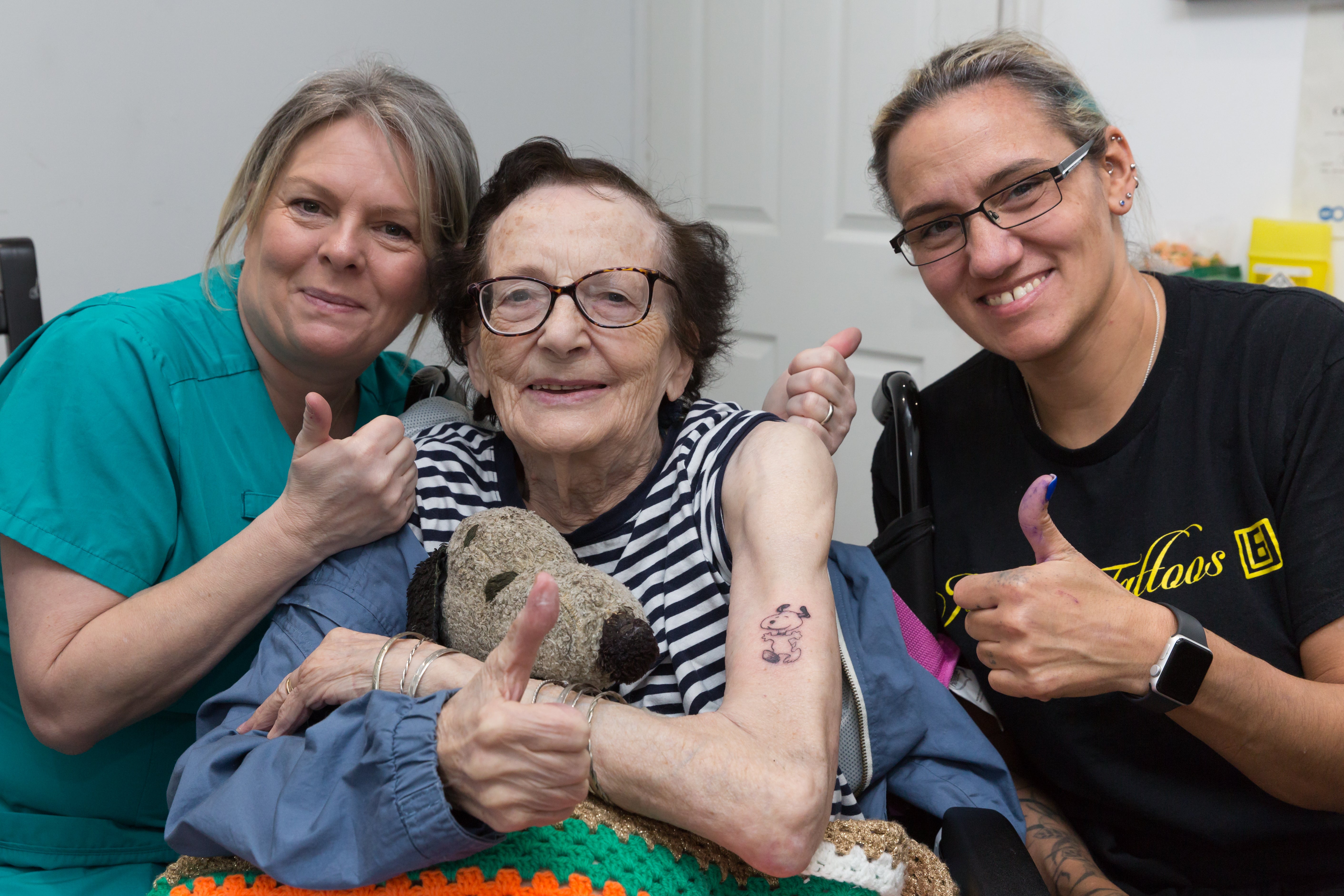 Dorothy France (centre), a resident at Care UK's The Burroughs in West Drayton, west London, who has fulfilled her teenage dream after getting her first tattoo of cartoon dog Snoopy