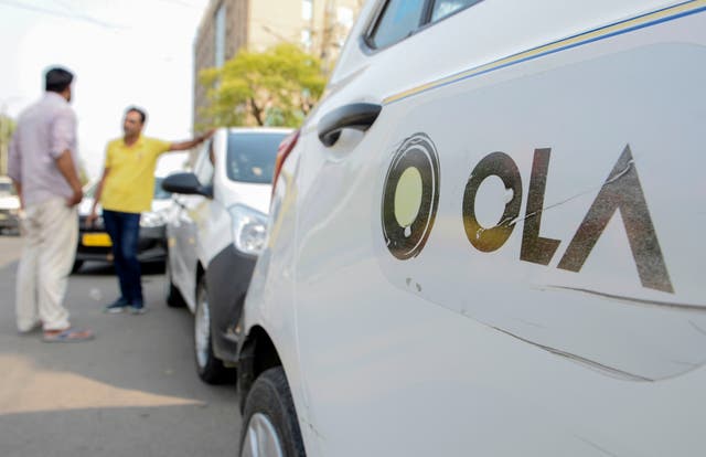 <p>In this photograph taken on September 12, 2019, Ola cab drivers talk with each other as they wait for passengers by a roadside in Amritsar</p>