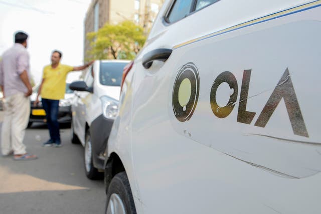 <p>In this photograph taken on September 12, 2019, Ola cab drivers talk with each other as they wait for passengers by a roadside in Amritsar</p>