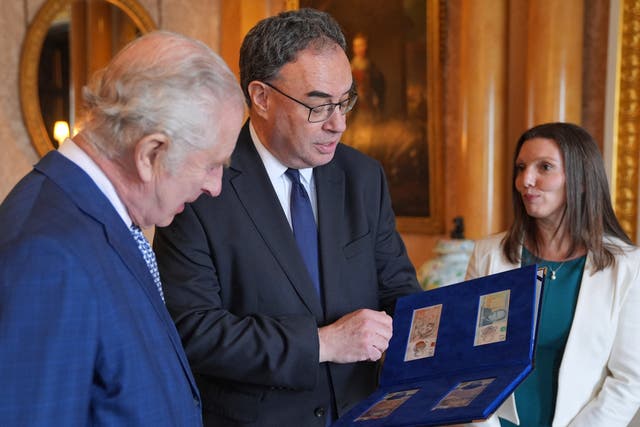 <p>King Charles III (L) is reacts as Bank of England Governor Andrew Bailey (C) and Bank of England's Chief Cashier Sarah John present him with the first bank notes featuring his portrait, at Buckingham Palace in London on April 9, 2024</p>
