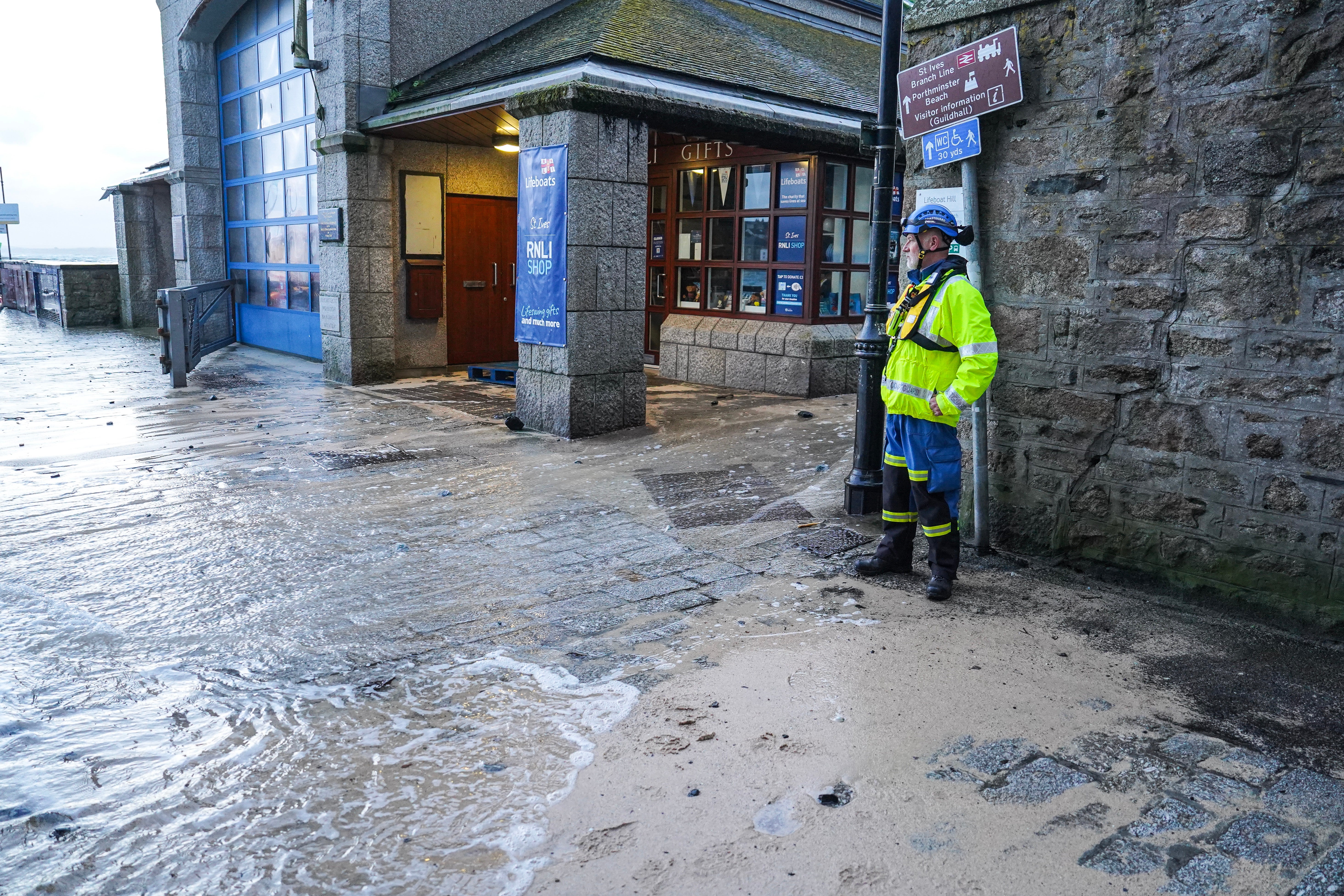 A member of HM Coastguard watches floodwater on the harbourside in St Ives, Cornwall